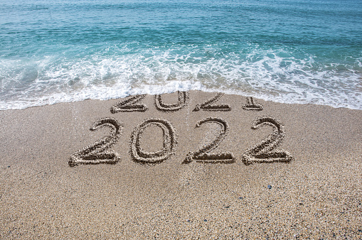 2022 written on sandy beach with waves